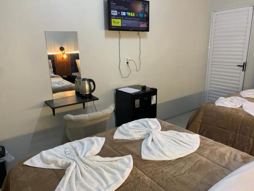 two beds in a room with a tv on the wall at Pousada HG-102-Suíte in Vila Nova do Sul