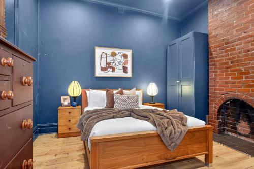 a blue bedroom with a bed and a brick wall at Ada Art Deco by Host Solutions Hutt St, Heritage in Adelaide