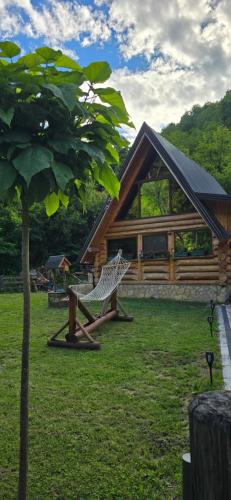a wooden cabin with a tree in the yard at Brvnara Floridita u prirodi - blizu Manastira Tavna in Ugljevik