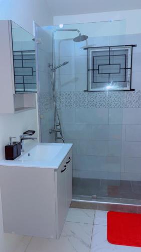 a white bathroom with a shower and a sink at Escape casa Ja in Portmore