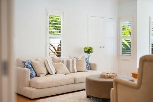 a white living room with a couch and a table at Winders Beach House in Marcoola