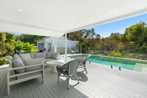 a deck with a couch and chairs and a pool at Winders Beach House in Marcoola