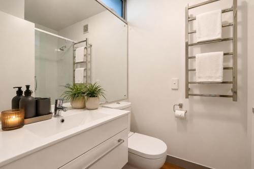 a white bathroom with a toilet and a sink at Lake & Mountain Views, Close to Shops & Dining in Queenstown