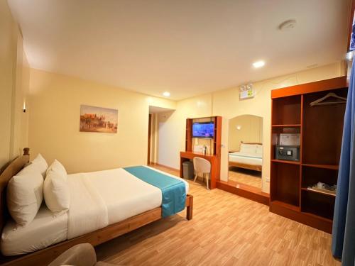 a hotel room with a bed and a television at Rufana Suites in Moalboal