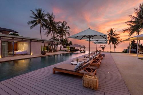 a pool with chairs and umbrellas next to a resort at Villa Amarelo in Ban Han Pa To