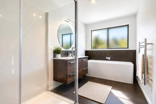 a bathroom with a tub and a sink and a mirror at Spacious Modern Retreat, Near Shops & Cafes in Queenstown