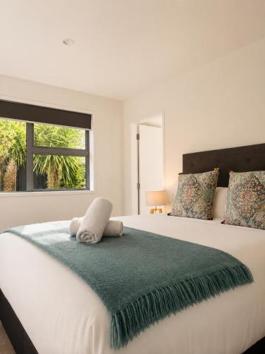 a bedroom with a large white bed with a window at Spacious Modern Retreat, Near Shops & Cafes in Queenstown