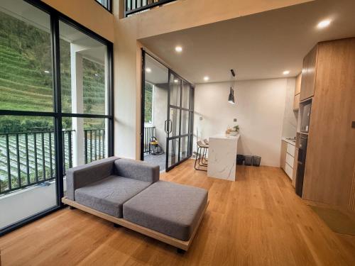 a living room with a couch and large windows at Singgah Sejenak Dieng in Diyeng