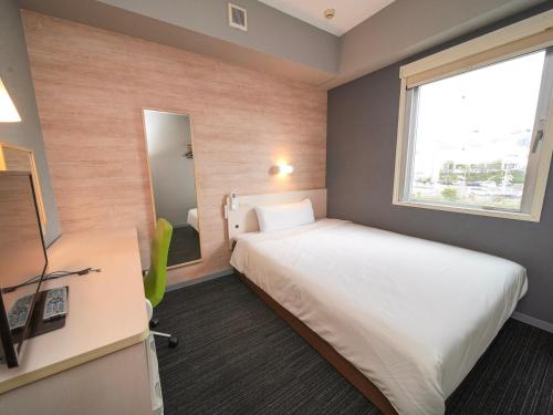 a bedroom with a bed and a desk and a window at Super Hotel Kofu Showa Inter in Showa