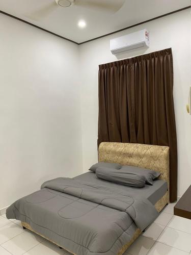 a bed in a white room with a curtain at PL Homestay 2 in Padang Lembu