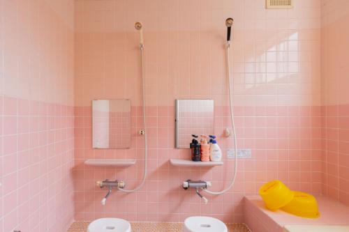 a pink bathroom with two sinks and a shower at ペンションレークサイド in Otsu