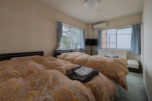a bedroom with two beds and a window at ペンションレークサイド in Otsu
