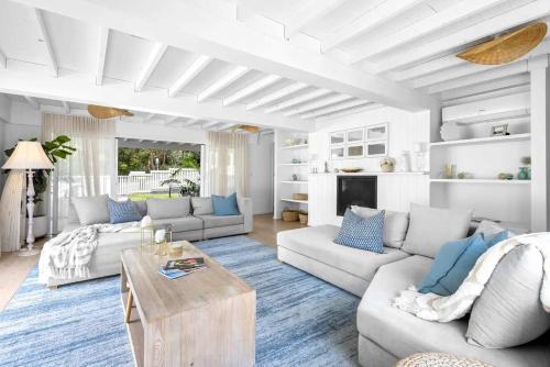 a living room with white furniture and blue pillows at Barra Luxe Beach House 4BR Yaroomba Beach Stay in Yaroomba
