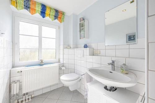 a white bathroom with a toilet and a sink at Fewo-Inselblick in Nordstrand