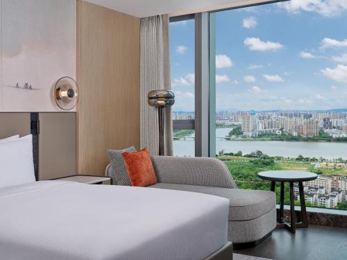a bedroom with a bed and a couch and a large window at Hilton Huizhou in Huizhou