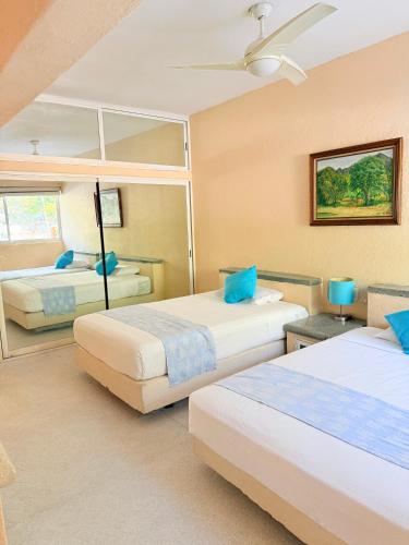 a bedroom with two beds with blue pillows at Villa Linda in Acapulco