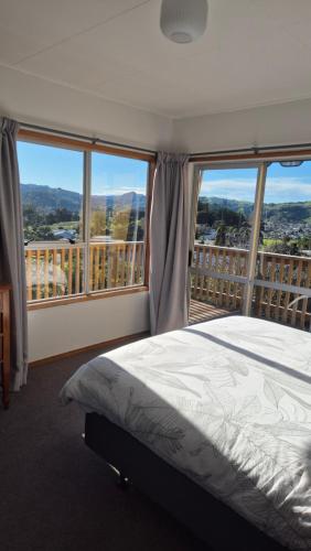 a bedroom with a bed and a balcony with views at Turanga Heights in Gisborne