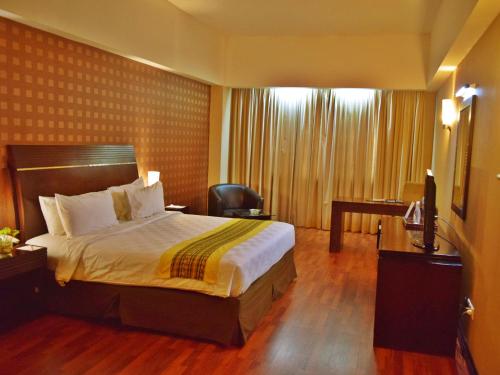 um quarto de hotel com uma cama e uma cadeira em Grand Elite Hotel Pekanbaru em Pekanbaru