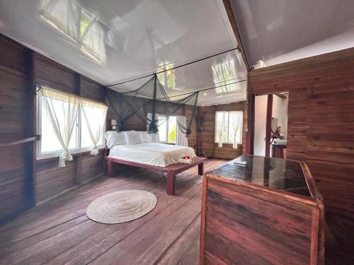a bedroom with a bed in a room with wooden floors at Coco cabañas Tela in El Triunfo de la Cruz