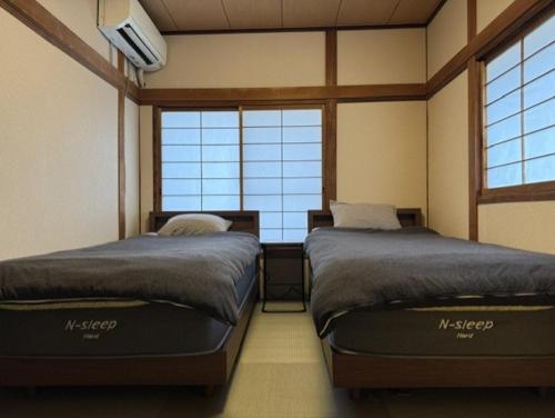 two beds in a room with two windows at 民泊利休 in Sakai