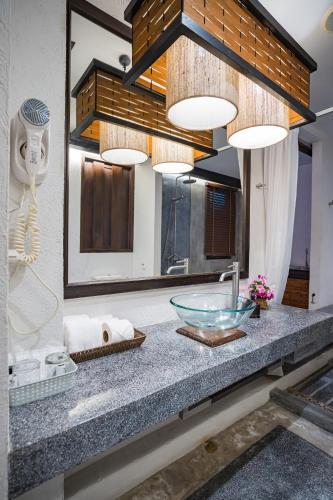 a bathroom counter with a bowl sink and a mirror at De Lanna Hotel in Chiang Mai