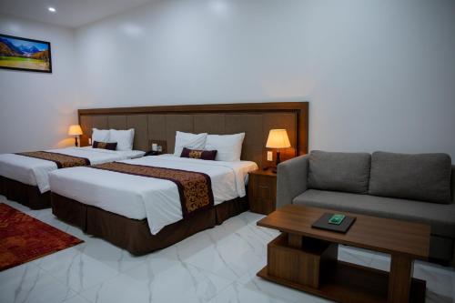 a hotel room with two beds and a couch at Nhat Quang Hotel in Bảo Lộc