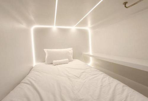 a white room with a bed with lights on it at The Rich Cafe & Hostel in Pattaya South