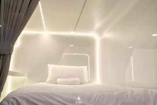 a white room with a bed with a white pillow at The Rich Cafe & Hostel in Pattaya South