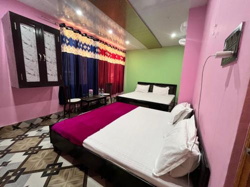 a bedroom with two beds and a pink and green wall at Hotel Manimahesh Bharmour in Brāhmaur