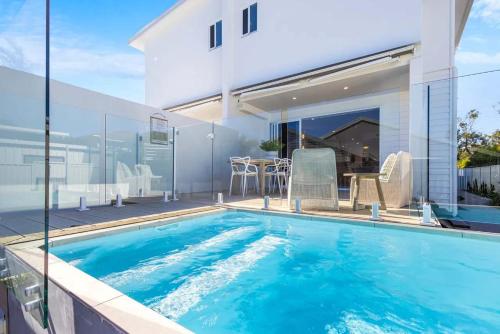 a swimming pool in front of a house at Key West Beach House in Coolum Beach
