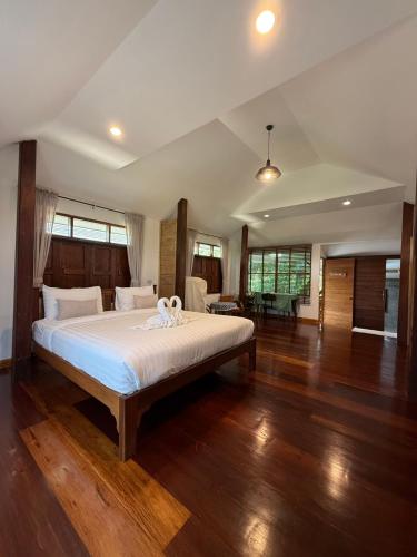 a bedroom with a bed with white sheets and wooden floors at เพลินนะเพลินนา รีสอร์ต Ploennaploenna in Ban Rim Lao