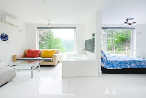 a white living room with a bed and a couch at Pygmalion Effect in Chuncheon