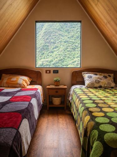 two beds in a room with a large window at Refugio Salkantay collpapampa in Colcapampa