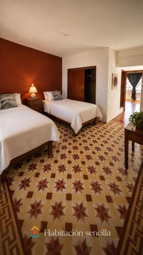 ein Hotelzimmer mit zwei Betten und einem gemusterten Boden in der Unterkunft Suite Afif Centro in Tlatlauquitepec
