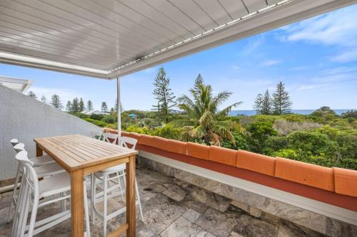 a porch with a table and chairs and a view of the ocean at Peregian Beach Apartment in Peregian Beach