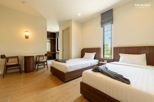 a hotel room with two beds and a table at The Regent Studio Kamala in Kamala Beach