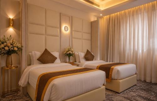 two beds in a hotel room with flowers on the wall at Qasr Arin Aprtments For Serviced Apartments شقق قصر ارين للشقق المخدومة in Jeddah
