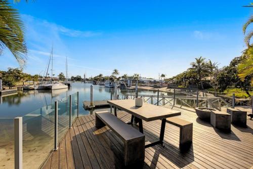 a wooden deck with a table and benches and a marina at Hampton Beach House on the Waterfront in Buddina