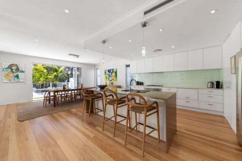 a kitchen with white cabinets and a table and chairs at Seaside Beach House in Marcoola
