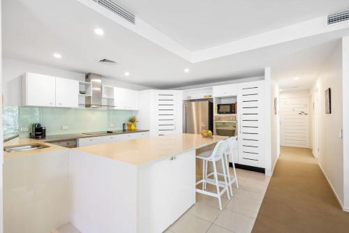 a white kitchen with white cabinets and a counter at Peregian on the Beach Apt 1 in Peregian Beach