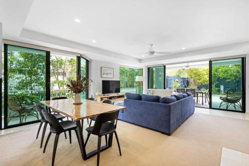 a living room with a blue couch and a table and chairs at Peregian on the Beach Apt 1 in Peregian Beach