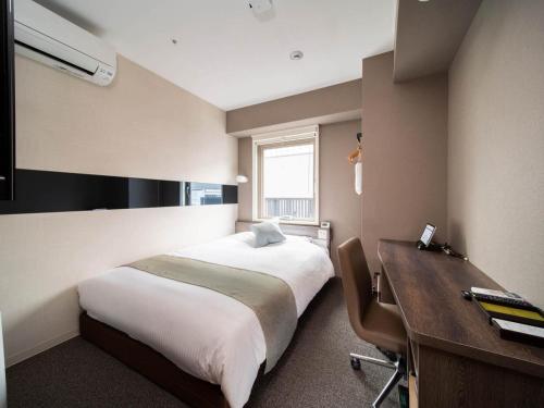 a hotel room with a bed and a desk and a desk at Super Hotel Premier Ginza in Tokyo