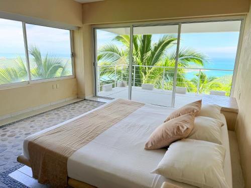 a bedroom with a large bed and large windows at Rincon Frente al mar in Acapulco