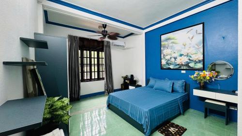 a blue bedroom with a bed and a ceiling fan at Favos Bích Động in Vũ Lâm