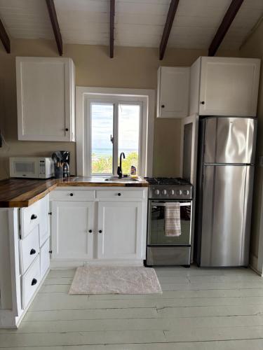 a kitchen with white cabinets and a stainless steel refrigerator at Solea by The Sea in Roatán