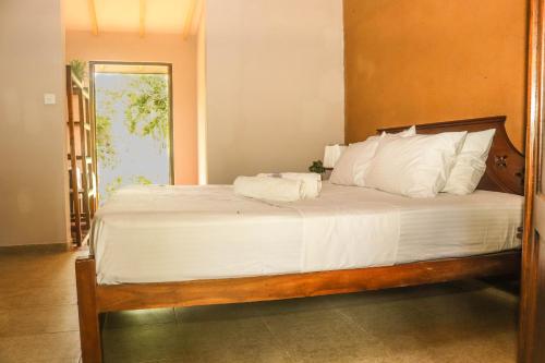 a bedroom with a large bed with white sheets at Unawa Retreat in Tissamaharama