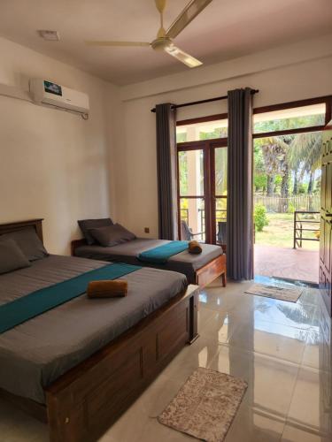 a bedroom with two beds and a balcony at Trinco salli beach resort in Trincomalee