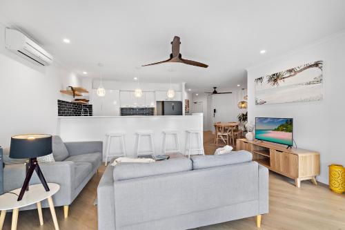 a living room with two couches and a tv at Serenity Apartments Noosa in Noosa Heads