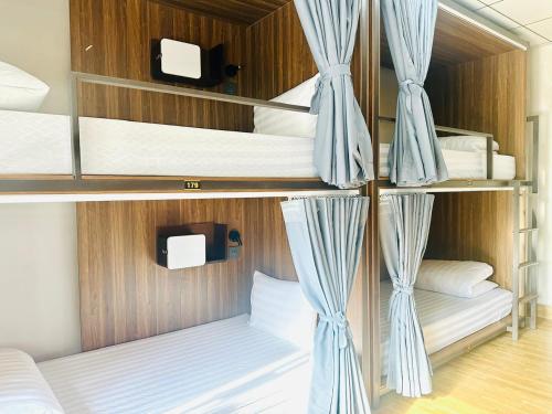 a room with three bunk beds with blue curtains at Central Backpackers Hostel - Phong Nha in Phong Nha