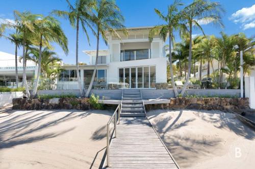 a house on the beach with palm trees and a boardwalk at Lucy - Noosa - Noosaville in Noosaville